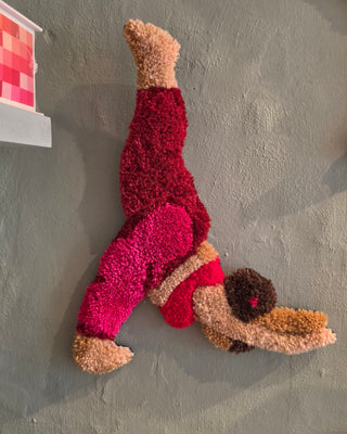 Vægtæppet Henriette er en del af en herlig serie af fitnesstrunter fra Raaholts Tuft, der hylder bevægeglæde, farver og det gode humør. Denne udgave viser figuren Henriette i en flot, omvendt yogastilling med armene strækt mod jorden, iført en rød top og bukser i en dyb, mørkerød nuance.
