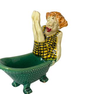 Figuren forestiller en person, der sidder i et badekar i en legende og lidt skæv positur. 