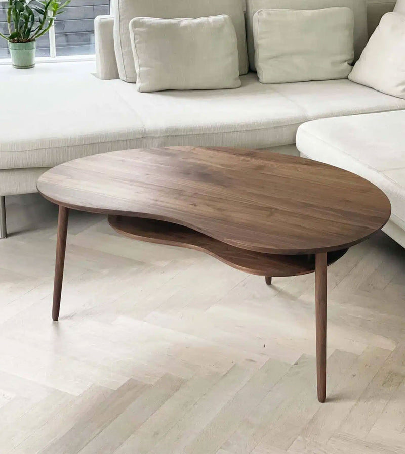 Elegant Bønnebord sofabord i massiv valnød, stor model med høj hylde, designet af Karsten Lauritsen. Dette luksuriøse designer sofabord fremhæver valnøddetræets varme glød og har en karakteristisk organisk form. Perfekt som et stilfuldt og funktionelt midtpunkt i stuen. Se vores udvalg af Bønneborde i massiv valnød her.